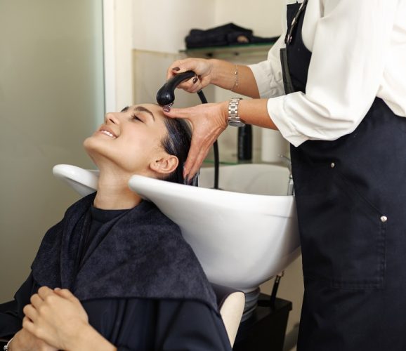 Hairdresser washes woman's hair, hairdressing salon. Stylist and client in hairsalon. Beauty business, professional service