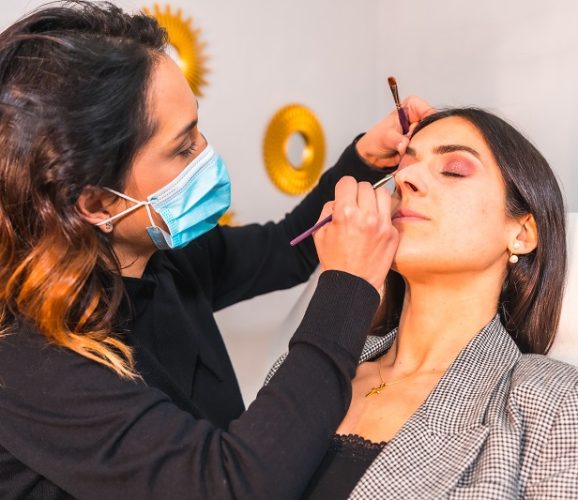 Detail of a makeup artist with a face mask making up the client's eyes. Reopening with security measures of aesthetic centers in the Covid-19 pandemic